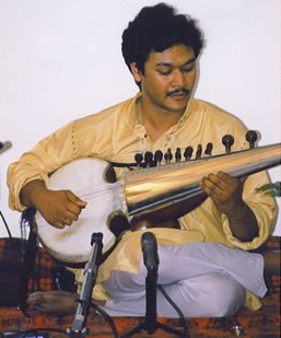 A man playing an instrument while sitting on the floor.