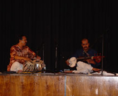 Two people playing instruments on a stage.