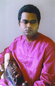 A man in pink shirt holding a guitar.