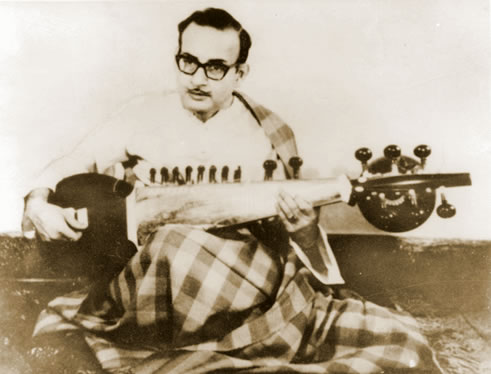 A man sitting on the ground playing an instrument.