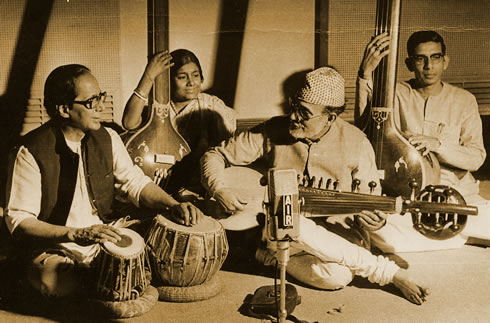 A group of people sitting around playing musical instruments.