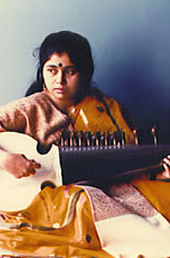 A woman playing an instrument in front of a wall.