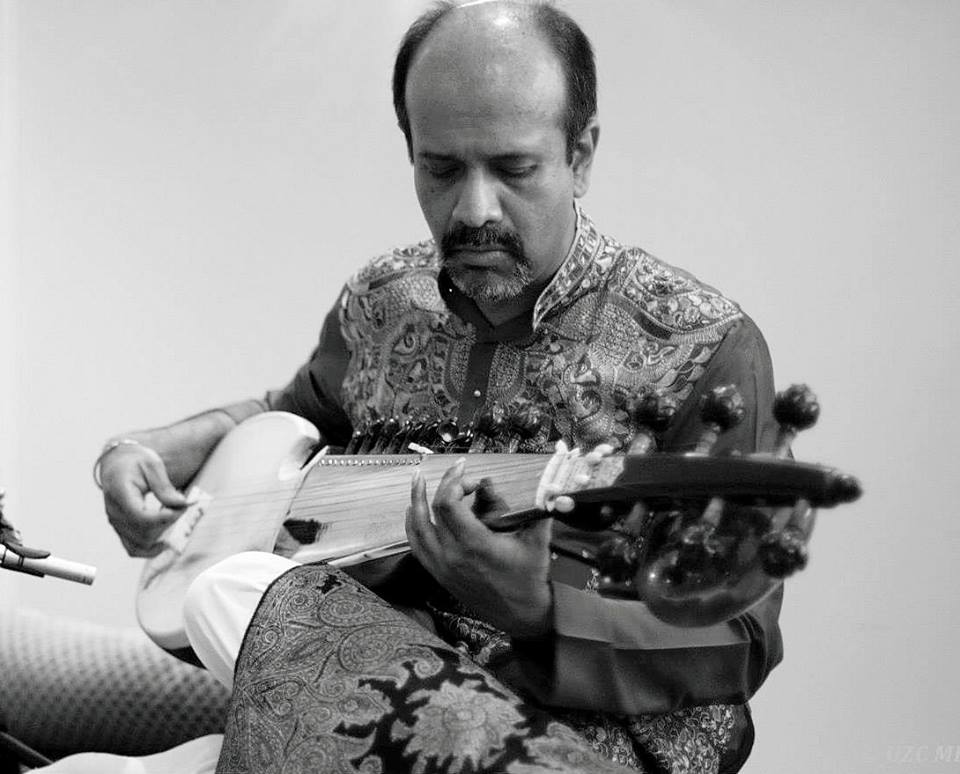 A man playing an instrument in front of a white wall.