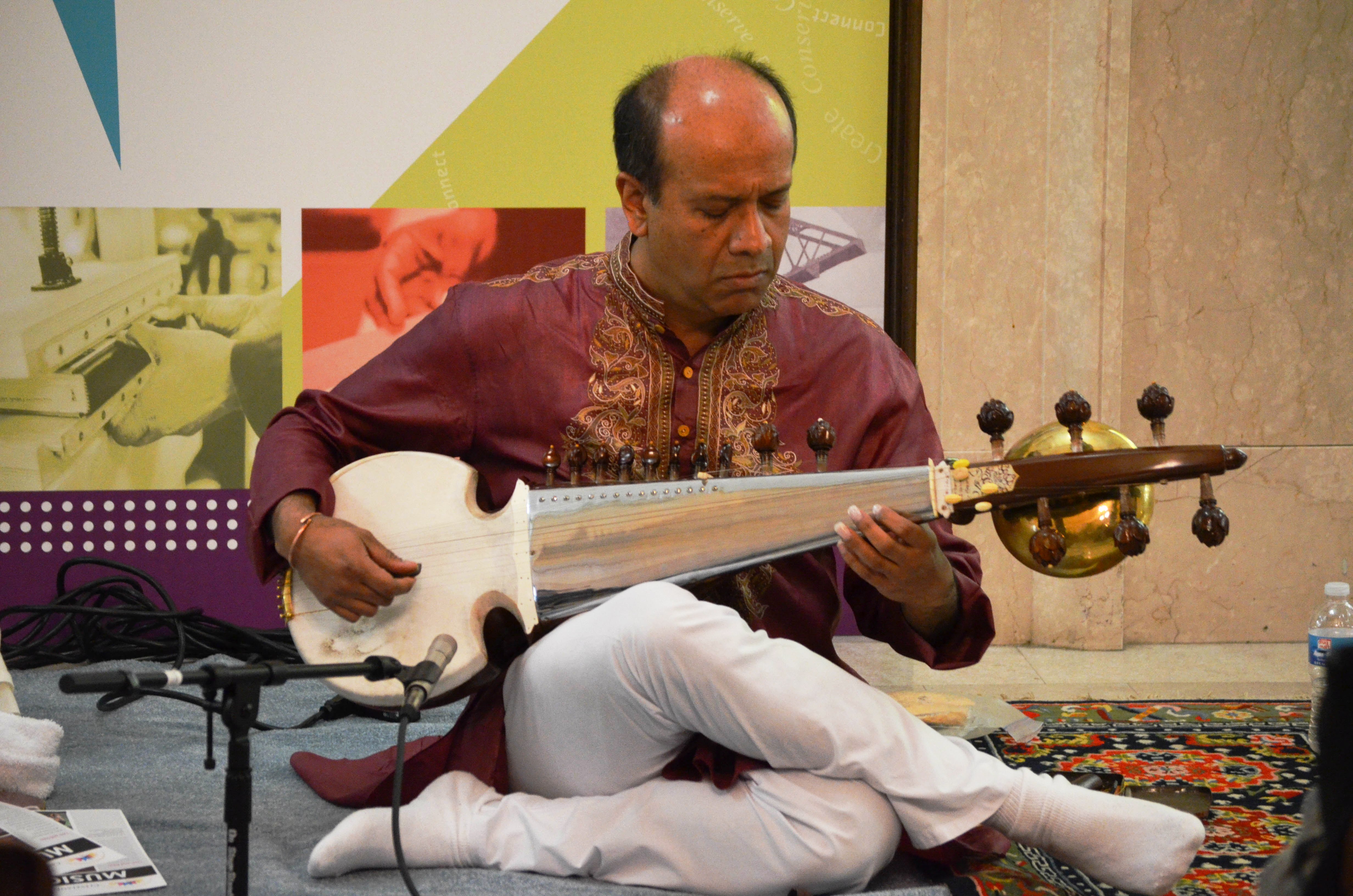 A man playing an instrument while sitting on the floor.