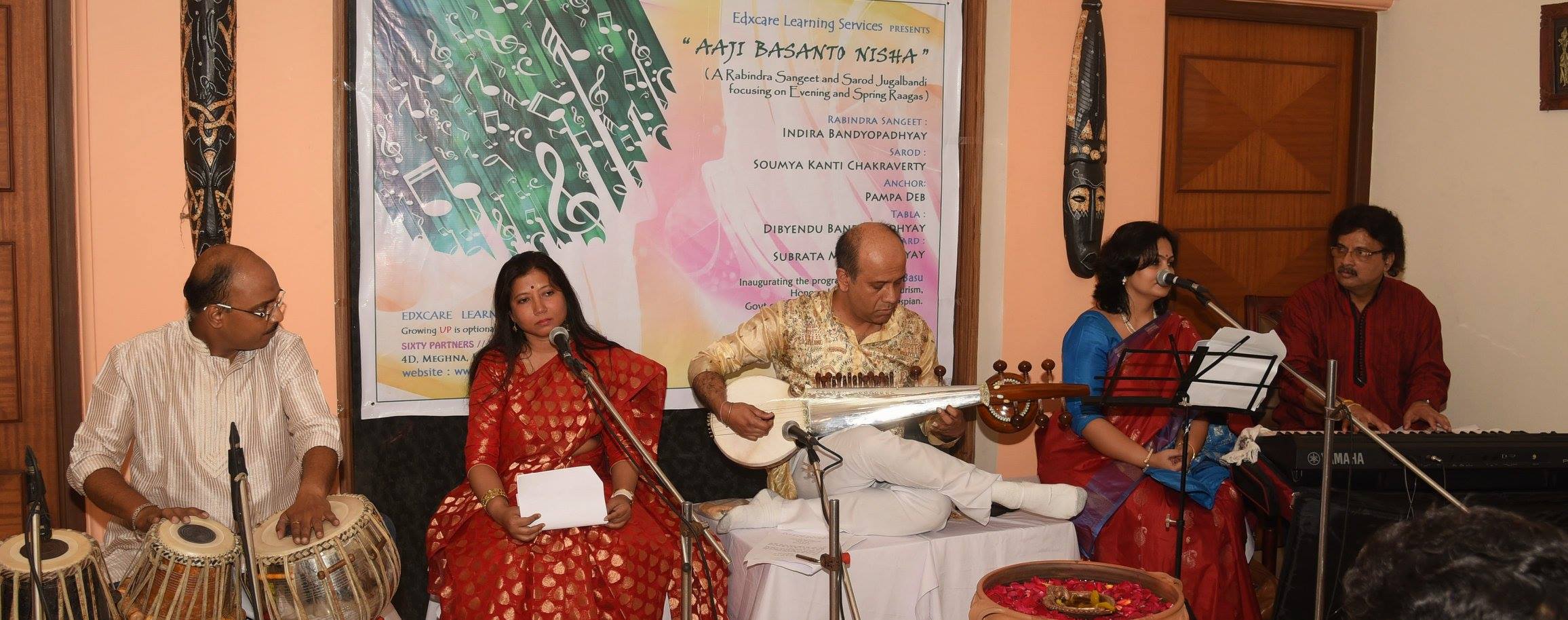 A man playing an instrument while two women sing.
